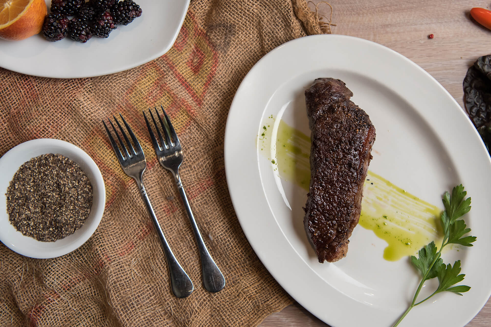 Cooked steak on a white plate with a sprig of parsley.