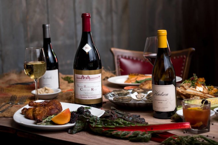 Three bottles of wine on a dining table with appetizers.
