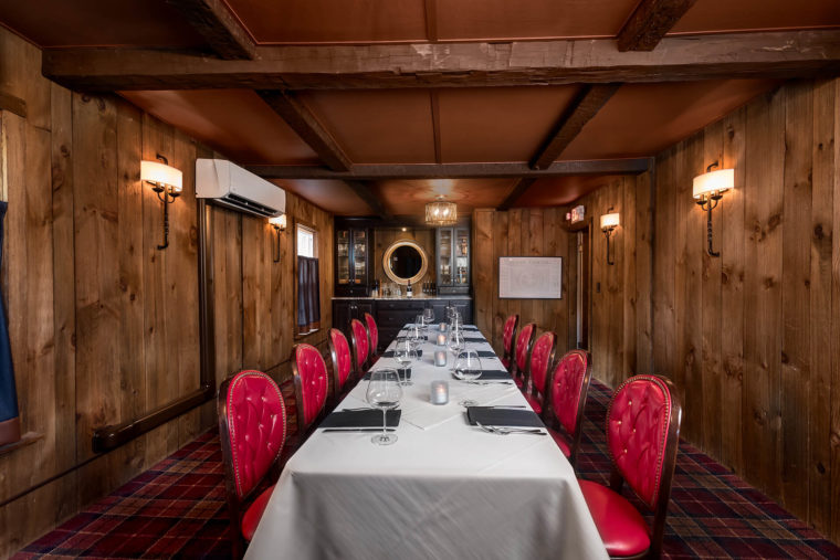 Room with a long dining table and red leather backed chairs.