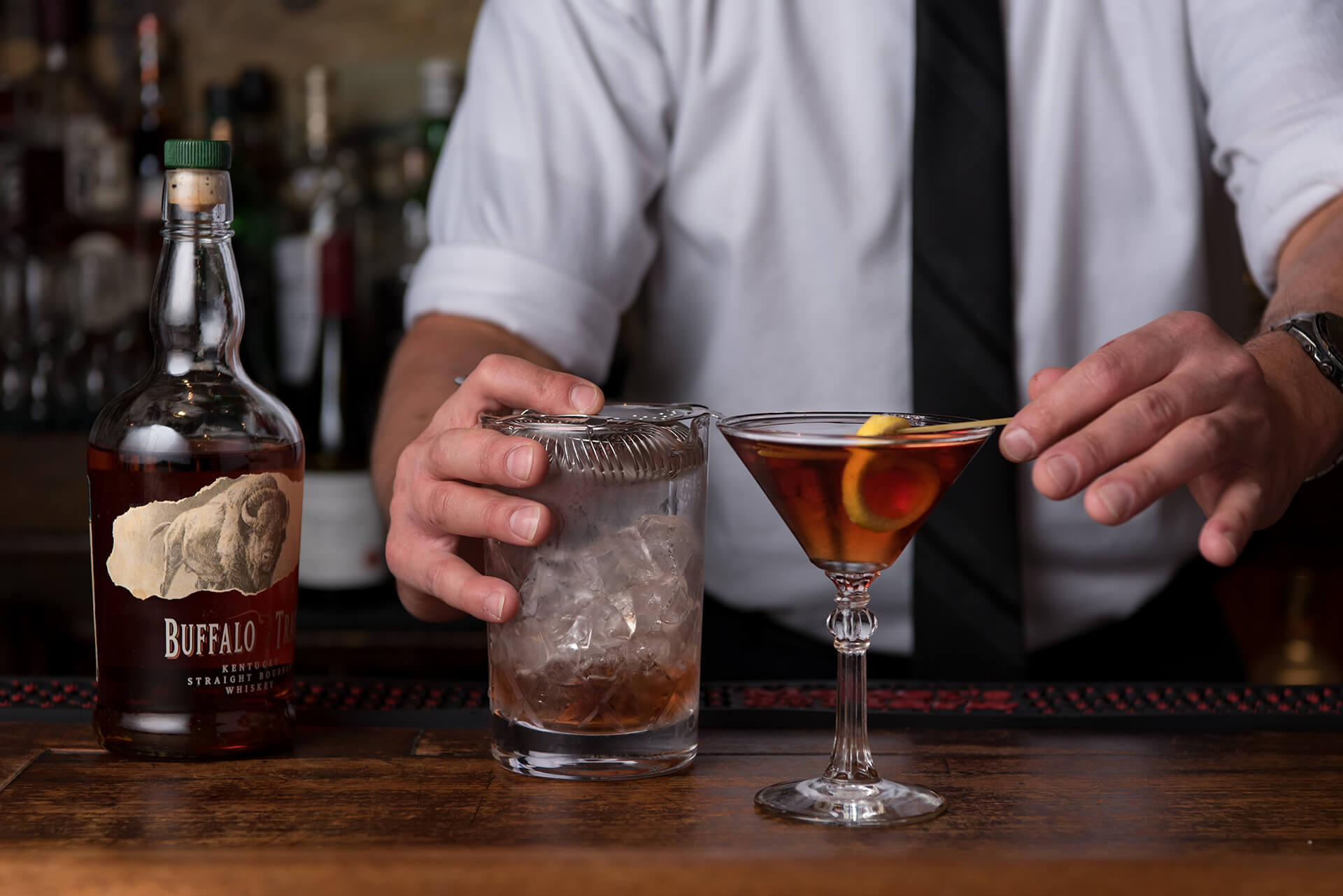 Bartender holding a large glass with ice and liquor.