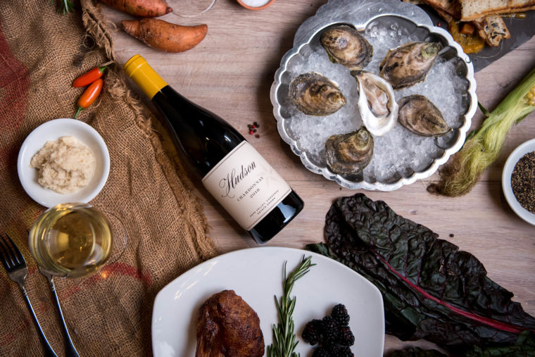 White wine bottle laying on a table next to a plate of oysters.