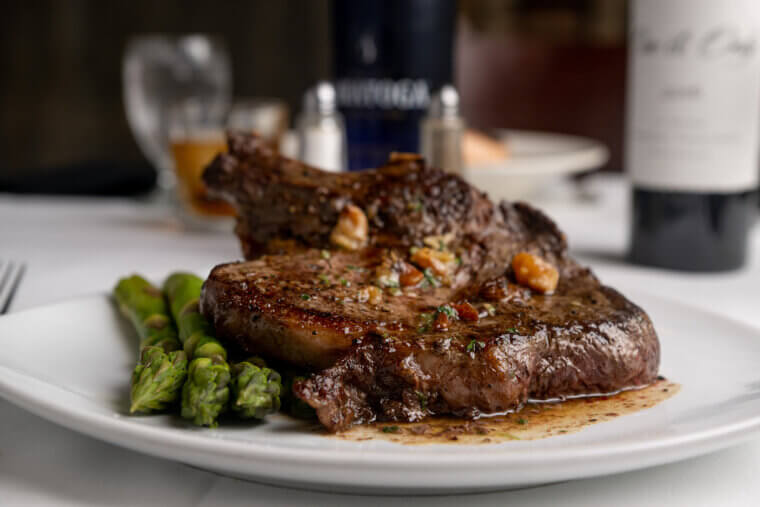 Cut of steak prepared with a glaze over asparagus.